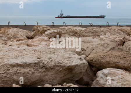 Mangystau, Kazakistan: Mar Caspio. Porto marittimo di Bautino. Petroliera in acqua. Blocchi di cemento e pietre di molo. Foto Stock