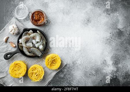 Tagliatelle con ingredienti di pesce, su sfondo grigio in pietra, vista dall'alto in piano, con spazio per la copia del testo Foto Stock