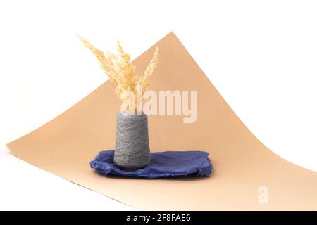 Erba secca di pampas a imitazione di vaso fatto di filo o filo di babina grande, carta di tessuto blu, bianco per interni di design in stile boho o scandinavo Foto Stock