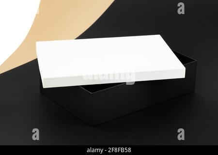 modello in stile minimalista di una grande scatola nera con coperchio bianco su sfondo di carta beige, nera e bianca Foto Stock