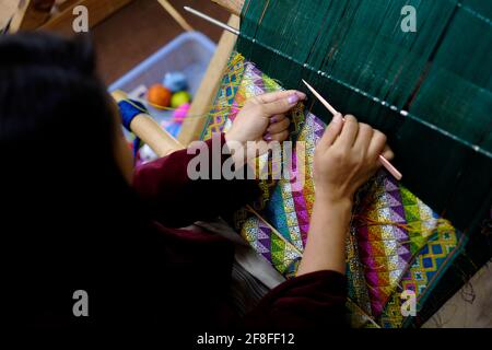 Un tessitore lavora su un tappeto tradizionale in città Di Thimphu in Bhutan Foto Stock