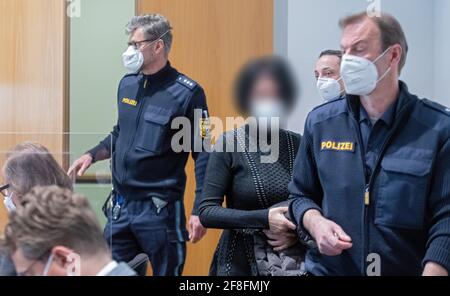 Augusta, Germania. 14 Apr 2021. Due agenti di polizia conducono una donna accusata nella sala della giuria. Gli imputati sono accusati di aver accusato le compagnie di assicurazione di assistenza infermieristica di milioni di persone tramite fatturazione per i servizi di assistenza che non sono stati forniti. Credit: Stefan Puchner/dpa - ATTENZIONE: Gli imputati sono stati pixelated per ordine della difesa/dpa/Alamy Live News Foto Stock