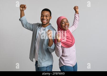 Coppia impressionabile afroamericana che celebra il successo, i pugni clenching e la danza Foto Stock