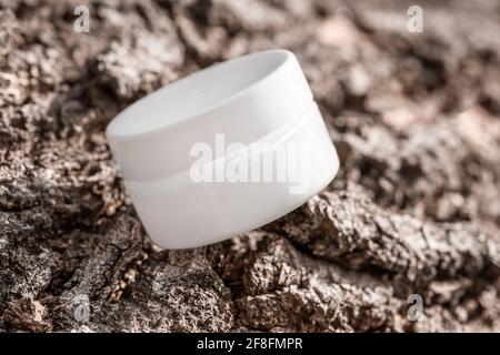 Bottiglia di crema cosmetica bianca su fondo di corteccia dell'albero Foto Stock