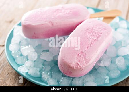 Popsicle di fragole e ghiaccio tritato su tavola di legno Foto Stock