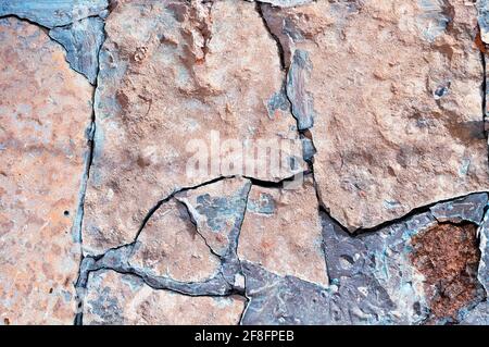 Fondo di pietra, pietra rosa pallido rotta vecchia con profonde crepe turchesi Foto Stock