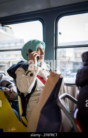 Donna musulmana che cavalcano i trasporti pubblici in città Foto Stock