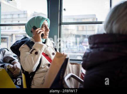 Donna musulmana che cavalcano i trasporti pubblici in città Foto Stock