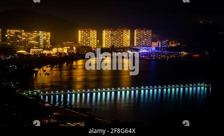 Sanya paesaggio notturno panoramico con lungo pontile nella Baia di Sanya e. Banshan penisola vista in Sanya Hainan isola Cina Foto Stock