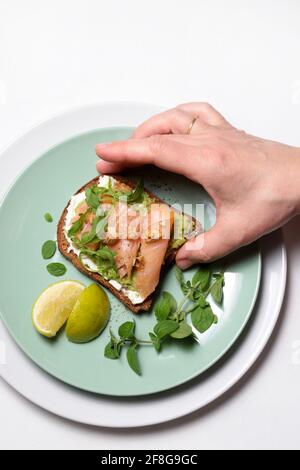 Sano avocado toast con salmone e formaggio su sfondo bianco. Direttamente sopra. Messa a fuoco selettiva. Foto Stock