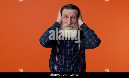 Non voglio sentire e ascoltare, irritato anziano uomo che copre le orecchie e gesturing no, evitando consigli Foto Stock