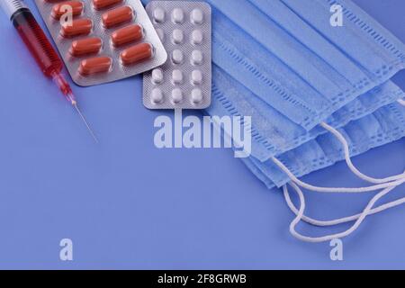 Maschera medica protettiva, pillole, siringa su sfondo blu, protezione da virus corona, coronavirus, covid19 pandemia globale Foto Stock