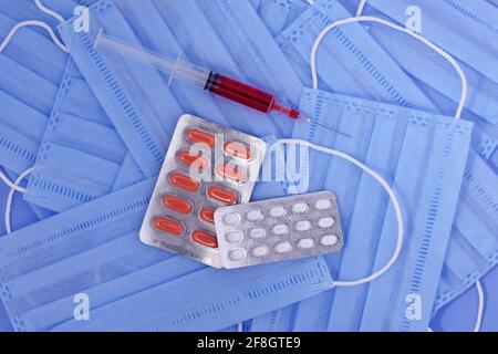 Maschera medica protettiva, pillole, siringa su sfondo blu, protezione da virus corona, coronavirus, covid19 pandemia globale Foto Stock