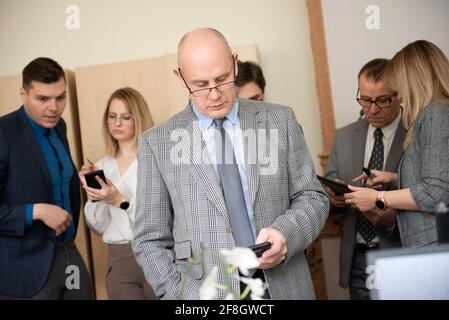 Uomo d'affari che usa il telefono cellulare con i colleghi in ufficio Foto Stock