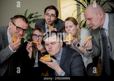 Business, cibo, pranzo e concetto di persone - Happy business team di mangiare la pizza in ufficio Foto Stock