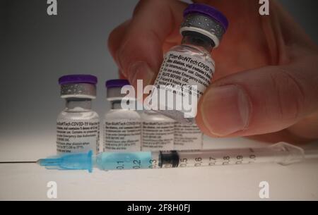 flaconcino di vaccino comirnaty originale disposto in un gruppo davanti di un backrop bianco con una siringa davanti a. loro Foto Stock