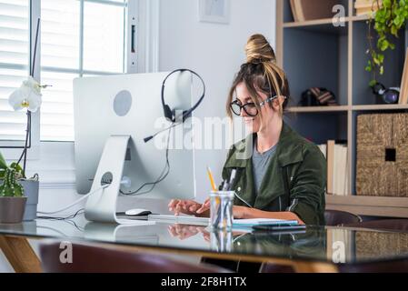 Donna caucasica adulta felice in uno sguardo professionale al computer portatile schermo lavoro on-line sul gadget da casa ufficio. Sorridente giovane femmina usa computer browse int Foto Stock