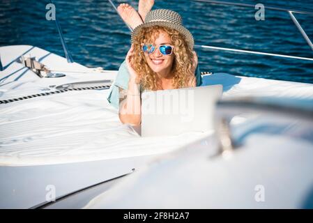 Donna sorriso posa sul ponte della barca in vacanze estive vacanza e guardare portatile - concetto di gratuito stile di vita moderno bella gente femminile - compu Foto Stock