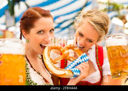 Giovani donne in tradizionali abiti bavarese - dirndl o tracht - su un festival o Oktoberfest in una tenda di birra Foto Stock