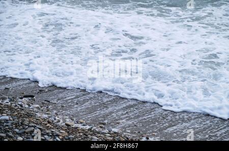 Condimenti di mare delicatamente ondulato e onde con schiuma bianca. Blu e talvolta turchese freddo Mare del Nord rotola su spiaggia di ciottoli. L'aria è fredda e fredda Foto Stock