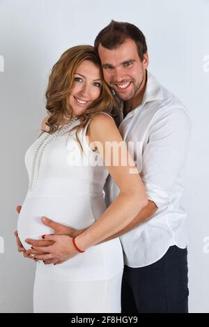 Felice coppia incinta vestito di bianco su sfondo bianco Foto Stock