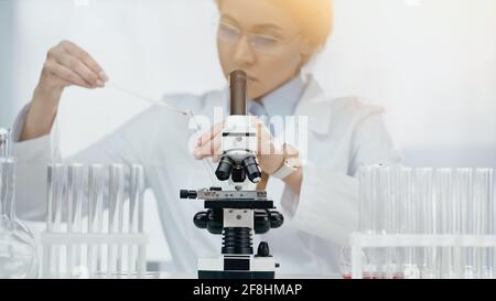 microscopio vicino afroamericano scienziato in vetri che tengono il campione sopra sfondo sfocato Foto Stock