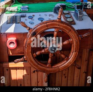 Volante e quadro di comando yacht. Pronto a viaggiare in mare. Coperta in legno all'interno della barca a vela. Nave sul molo. Bel tempo per navigare. Demre, Turchia - Foto Stock