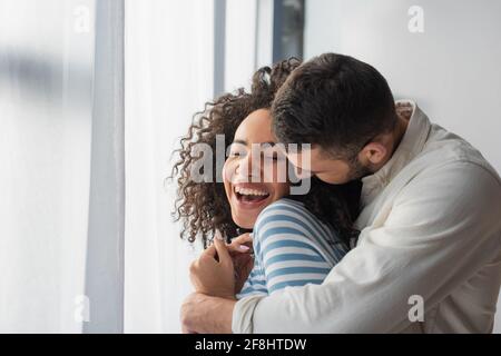 allegra coppia multietnica abbracciata a casa Foto Stock
