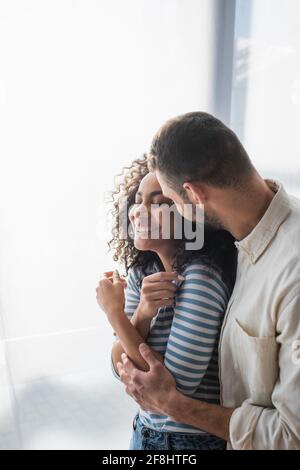 allegra coppia multietnica sorridente mentre si aggirava a casa Foto Stock