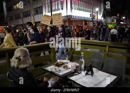 Philadelphia, Stati Uniti. 13 Apr 2021. Una cena all'aperto si siede e guarda mentre i dimostranti marciano durante una protesta di Justice for Daunte Wright a Philadelphia, USA. Daunte Wright era un uomo nero di 20 anni che fu ucciso e ucciso da un agente di polizia a Brooklyn Center, Minnesota, il 11 aprile. Credit: Chase Sutton/Alamy Live News Foto Stock