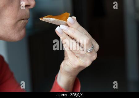 Primo piano su donna che mangia la colazione tenendo pita pane con la marmellata di pesche con la mano. Concetto di alimentazione sana Foto Stock