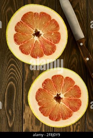 Taglio di pomelo rosso maturo su un tavolo di legno, vista dall'alto Foto Stock