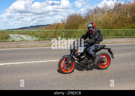 Suzuki Red 125cc; motociclista; due ruote trasporto, moto, veicolo su strade britanniche, moto, motociclisti moto motociclisti che automobilano a Manchester, Regno Unito Foto Stock