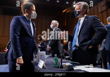 Washington, Stati Uniti. 14 Apr 2021. Christopher Wray, direttore dell'FBI, parla con il senatore americano Marco Rubio, democratico della Florida, prima di testimoniare durante un'audizione del Comitato di selezione del Senato sull'intelligenza sulle minacce mondiali a Capitol Hill a Washington, DC, il 14 aprile 2021. Foto della piscina di Saul Loeb/UPI Credit: UPI/Alamy Live News Foto Stock