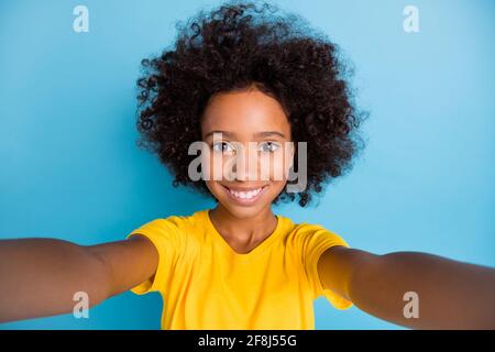 Foto di affascinante bella bambina poco scura di pelle fare selfie blogger isolato su sfondo di colore blu pastello Foto Stock