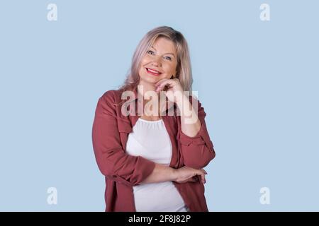 bionda uomo d'affari senior sta posando su una parete blu dello studio sorridendo alla macchina fotografica Foto Stock