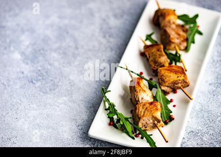 Spiedini di maiale alla griglia con foglie di rucola Foto Stock