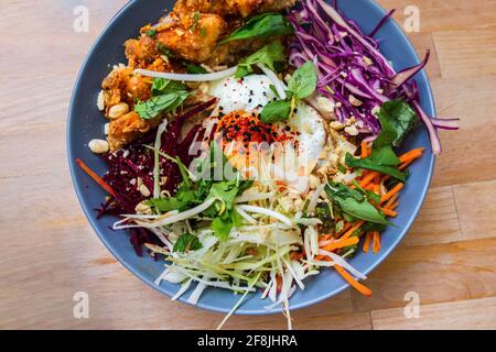 Pasto asiatico con verdure grattugiate grattugiate (lattuga, cavolo, carota), erbe verdi, uova sode e pezzi di pollo in pangrattato. Foto Stock