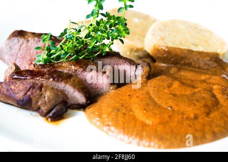 Carne di cervo, salsa di pan di zenzero di prugne e gnocchi, pasto tradizionale della repubblica Ceca. Primo piano. Foto Stock