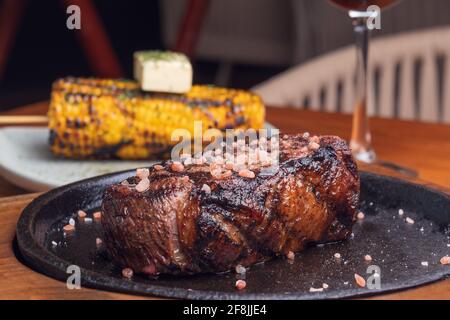 Bistecca alla griglia e guarnire il mais giallo su un tavolo di legno. Cibo gourmet. Foto Stock