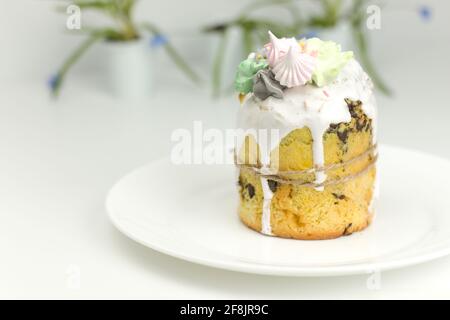 Torta di Pasqua ortodossa con fondente bianco e marshmallows legati con una corda su un piatto con fiori di primavera in un pentola Foto Stock