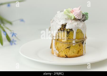 Torta di Pasqua ortodossa con fondente bianco e marshmallows legati con una corda su un piatto con fiori di primavera in un pentola Foto Stock