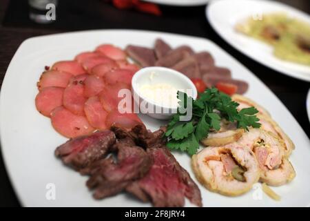 Fette di carne su un piatto bianco nel ristorante Foto Stock