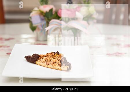 Un angolo di noce fatto in casa (pasticceria) su un piatto su un tavolo decorato. A destra è presente un ampio spazio per la copia. Sullo sfondo sono piccoli vasi di fiori con archi. Foto Stock