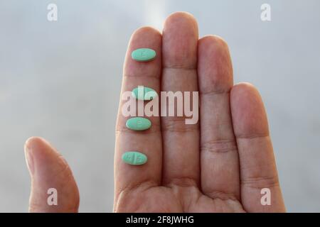 Macro shot di pillole di Losartan in una mano. È un farmaco di prescrizione utilizzato per trattare l'ipertensione, la pressione alta. Usato anche per aiutare i reni. Foto Stock