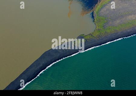 Vista aerea su Landeyjarsandur che mostra la spiaggia con sabbia vulcanica nera e acqua marrone carico di sedimenti che fluiscono in mare in estate, Islanda Foto Stock