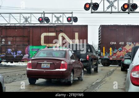 Bartlett, Illinois, Stati Uniti. Bloccati in inverno e temporaneamente ritardati da un treno merci in transito, gli automobilisti dell'Illinois aspettano che passi un treno merci. Foto Stock