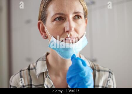 Medico che esegue il test di flusso laterale rapido per Covid-19 su Donna matura in chirurgia indossare maschera Foto Stock