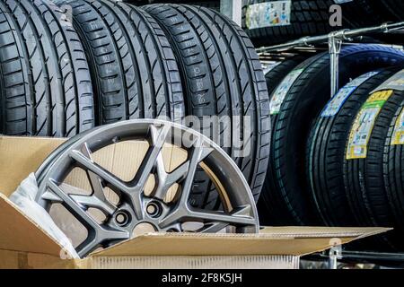 nuovo ed elegante cerchio in lega leggera in scatola di cartone sullo sfondo di nuovi pneumatici estivi Foto Stock