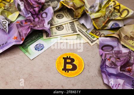 Moneta di carta con immagine di bitcoin su sfondo grigio. Banconote in contanti sbriciolati di dollari e euro intorno. Simbolo di spostamento e sostituzione di m reale Foto Stock